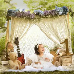 A moment of pure joy in a beautiful boho setting. This little girl's happy laugh is the highlight of this outdoor-style shoot, complete with a macrame tent, teddy bears, and a guitar.