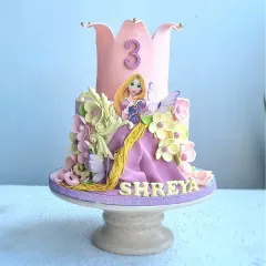 A full view of the Rapunzel princess cake. The purple and pink color scheme and intricate details bring the Disney story to life.