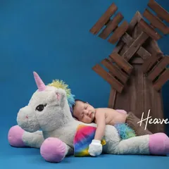 A magical moment with a mythical friend. Here, a sleeping baby rests peacefully on a large, soft unicorn plush, creating a whimsical and enchanting scene.