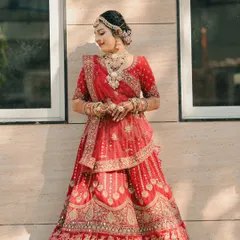 A classic portrait of the bride, looking radiant in the sunlight which highlights the beautiful mirror work on her red lehenga.