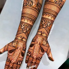 A classic full-arm bridal design featuring symmetrical patterns with peacock and architectural motifs.