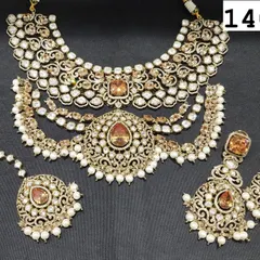 A close-up of a multi-layered Polki necklace set with champagne-colored stones and pearl drops. This set, which includes a choker, earrings, and maang tikka, is available for both rent and purchase.