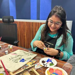 It's all in the details! A painter carefully chooses her colors for a beautiful floral design on a tote bag.