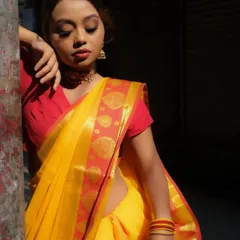 This look captures a soft, sun-kissed traditional style. The makeup is subtle, with a warm smokey eye and a soft red lip that complements the yellow and red banarasi saree.