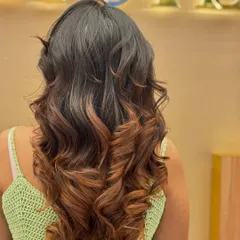 This back view shows a beautiful ombré effect, with the color gradually lightening towards the ends. The soft curls enhance the blend and create a glamorous finish.