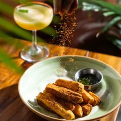 An action shot capturing the final touch. The sprinkling of seasoning over fries at Common House Karjat adds a dynamic element, making the food look fresh, interactive, and even more delicious.