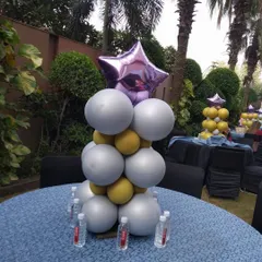 A stylish balloon centerpiece for a cocktail table. The combination of silver, gold, and a purple star foil balloon adds a touch of glamour to an outdoor event.