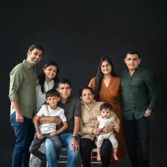 A full family portrait against a classic dark backdrop, creating a timeless and elegant look. The coordinated outfits in neutral tones help unify the image and keep the focus on their connection.
