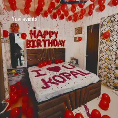 This is my classic romantic birthday room decoration. The setup includes red helium balloons covering the ceiling, 'HAPPY BIRTHDAY' foil letters above the bed, and a personal message like 'I ❤️ U' written with fresh rose petals on the bed.