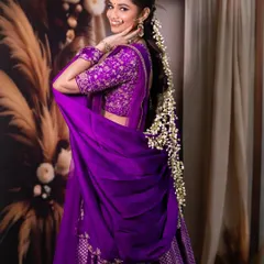 This shot captures a joyful, candid moment, highlighting the beautiful floral hair accessory and the elegant drape of the purple dupatta. It adds a touch of personality to a bridal series.