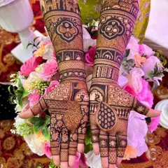 This design uses bold, dark henna to create a striking contrast. The artwork features prominent peacock figures on the palms and architectural patterns on the forearms, perfect for a statement bridal look.