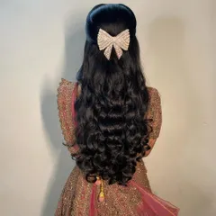 For a glamorous reception, I styled this client's hair in voluminous, bouncy curls. The look is completed with a modern, sparkling bow clip, creating a half-updo that is perfect for dancing the night away.