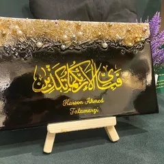 This personalized plaque features the verse "Fabi ayyi ala i rabbikuma tukazziban" in bold yellow calligraphy on a black background. The top is adorned with a textured mix of gold and silver embellishments, and it includes the client's name for a personal touch.