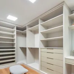 A different angle of a spacious walk-in closet layout. We focus on maximizing every corner with a combination of drawers, open shelving, and hanging areas to create a highly organized and accessible dressing room.