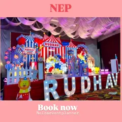 The main stage for a carnival-themed first birthday, featuring a Ferris wheel prop, circus tent backdrops, and large marquee letters of the child's name.