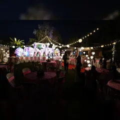 A wide-angle view of an outdoor birthday party at night, showing how string lights and paper lanterns create a warm and festive ambiance over the entire area.