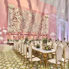 An incredible family dining experience set against an intricately crafted pith wall. The long marble tables are paired with elegant gold and cream chairs, while the floral centerpieces add a touch of softness to the grand setting.