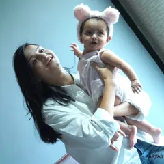 A mother holds her baby, who is wearing an adorable animal-ear headband. This photo from a "mom & me" session captures the tender bond between mother and child.