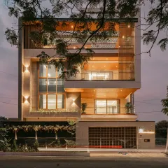 The Hennur Road residence at dusk, where strategic architectural lighting highlights the material textures and vertical lines. The warm light from within creates a welcoming glow, transforming the home's presence after sunset.