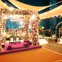 A stunning rooftop mandap setup, framed by pillars of beautiful pink and white flowers. This shows how our catering presentation integrates seamlessly with the main event decor to create a cohesive, beautiful space.