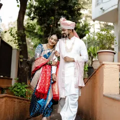 A beautiful shot of the couple walking together after their Marathi wedding ceremony. The bride's traditional blue Paithani saree and the groom's classic white kurta create a timeless look.