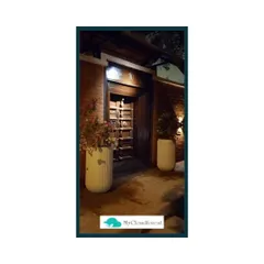 The right planters can make a statement. Here, two large, modern planters flank an entryway, with uplighting to highlight the plants and create a dramatic, welcoming effect at night.