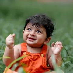Looking up at the world with wonder. The vibrant green grass makes the perfect backdrop for this happy baby.