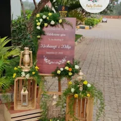 This rustic welcome setup uses wooden crates, vintage lanterns, and birdcages filled with flowers. The personalized wooden sign warmly greets guests, creating a charming and personalized entryway for the wedding.