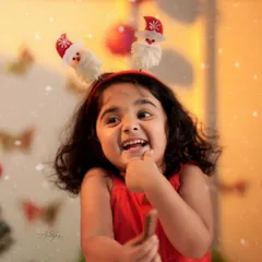 A close-up of a laughing girl wearing a cute Santa headband, with soft, warm Christmas lights creating a magical glow.