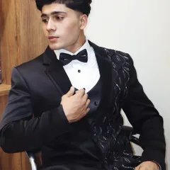 A unique take on the classic black tuxedo. This one features an asymmetric design with textured, raised fabric on one lapel, creating a modern and artistic statement piece.