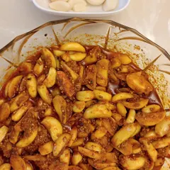 A bowl full of our Lehsun ka Achaar (Garlic Pickle). The garlic cloves are soft yet crunchy, and they are soaked in a tangy and spicy masala.