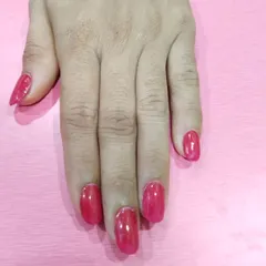 A classic, vibrant red-pink gel polish on medium-length nails. This is a timeless color that is both fun and elegant, suitable for any occasion.