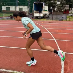 Getting into a starting stance on the track. This moment of focus before exploding off the line is critical for any speed work or race.