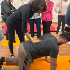 Hands-on learning is critical for understanding how to correct form. Here, I'm demonstrating proper spinal alignment in a quadruped position during our Mat Pilates instructor training.