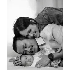 In the quiet moments, love speaks the loudest. This classic black and white portrait captures the profound bond between new parents and their sleeping baby, a memory to hold forever.