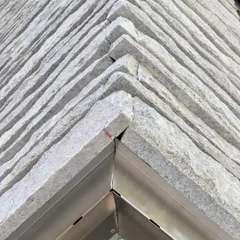 A corner detail of a hand-chiseled stone wall in progress. Stone is a geological material, and we work with it to express its weight, texture, and history, treating it as the skin of the building.