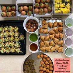 A vibrant and delicious spread of party starters for a Mehendi celebration. This order included crowd-pleasers like Aloo Peas Samosas, Khaman Dhokla, Mini Veggie Burgers, Mini Pizzas, Hara Bhara Kebabs, Corn and Cheese Balls, and sweet Gulab Jamun.