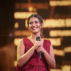 A beautiful candid portrait of actress Priya P. Varrier on stage. The warm lighting and her natural expression make this a standout shot from the awards night.