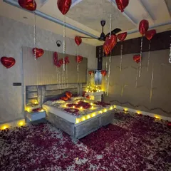 Another angle of a surprise room decoration, showing how the combination of floating balloons and a floor covered in petals instantly creates a festive and romantic mood.