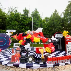 The central stage for the Ferrari party, featuring a giant red number '5', a checkered floor, a speedometer backdrop, and a vintage-style gas pump prop.