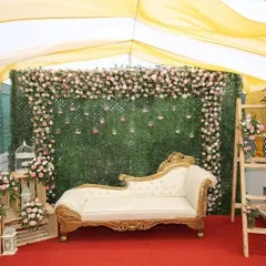 We specialize in creating beautiful settings for intimate events. This photo booth setup for a lockdown wedding features a lush green wall, a cascade of pink and white roses, and a classic chaise lounge for perfect pictures.