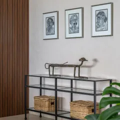 This vignette from Apartment 1600 showcases our curated approach to furnishing. A simple black steel and glass console is paired with woven baskets and distinctive artwork, creating an entryway that is both functional and expressive of a mid-century tropical aesthetic.