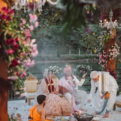 A couple shares a smile during their ceremony, seated under a magical ceiling of white flowers that feels like a cloud. We designed this space to feel like an enchanted forest, creating a warm and beautiful setting for their union.