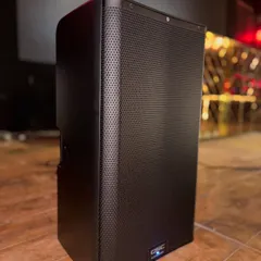 A close-up of a QSC K12.2 active loudspeaker, installed and ready to fill the room with powerful, clear sound. This is professional-grade equipment designed for live music and high-energy club environments.