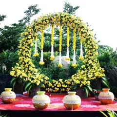 A stunning Haldi ceremony backdrop, featuring a full circle arch of bright yellow marigolds and hanging floral tassels. This setup provides a perfect, sun-kissed photo opportunity for the pre-wedding ritual.