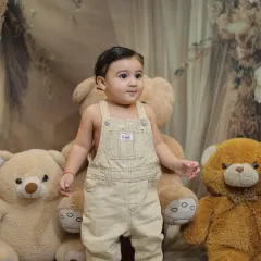A confident pose from a little boy in overalls, surrounded by his teddy bear friends. Our studio setups are designed to be fun and engaging for kids.