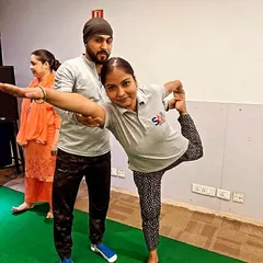 Providing a personal adjustment to an employee during a corporate yoga session. I ensure everyone feels comfortable and practices safely, even in a group setting.