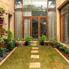 An internal courtyard in the Nivriti residence in Jakkur, Bangalore, serves as a private green oasis. We often incorporate such courtyards to improve natural light and ventilation, fostering a tranquil connection with nature within the home's footprint.