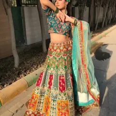 A full-length shot of a model wearing our multi-color Sangeet lehenga outdoors. The natural light brings out the rich colors and intricate threadwork of this stunning piece.