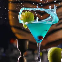 A dynamic splash shot of a blue cocktail, demonstrating the technical skill our commercial photographers use to create eye-catching imagery for bars, restaurants, and beverage brands.